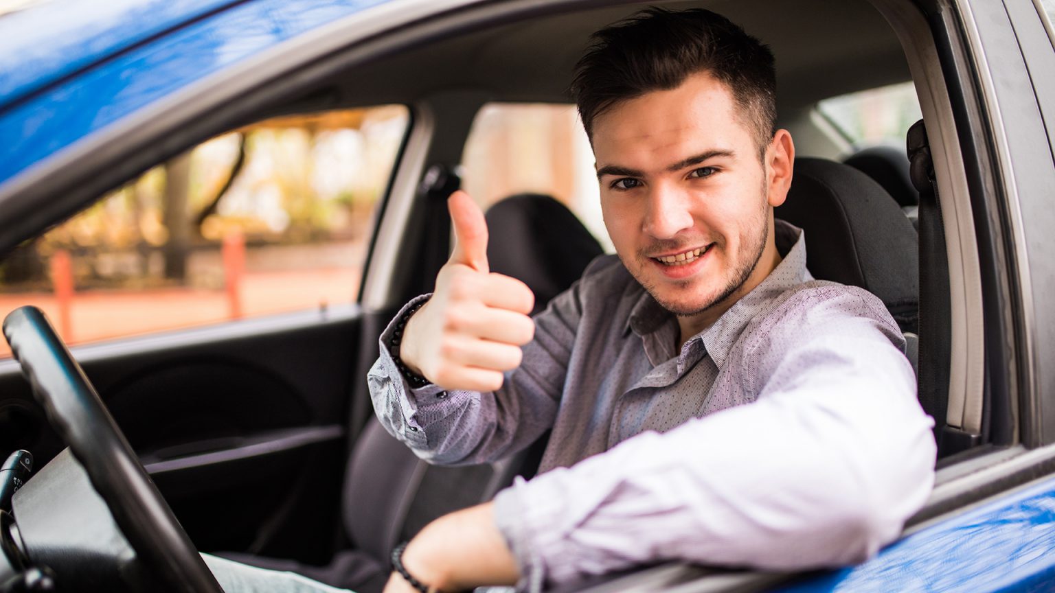 happy-smiling-man-sitting-inside-car-showing-thumbs-up-handsome-guy-excited-about-his-new-vehicle-positive-face-expression1-1536x864